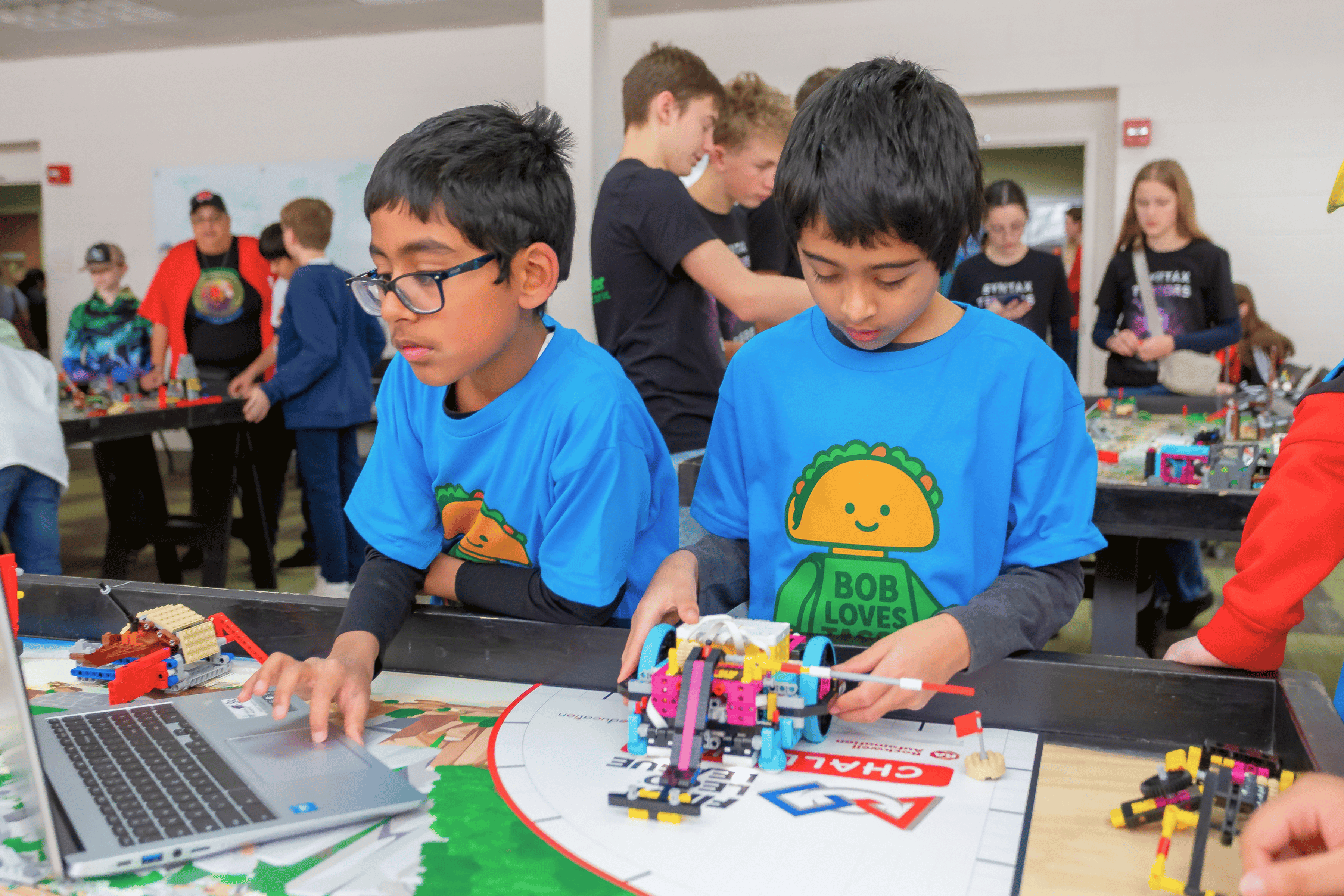 FIRST LEGO League participants making finishing touches on the LEGO robot at a tournament.