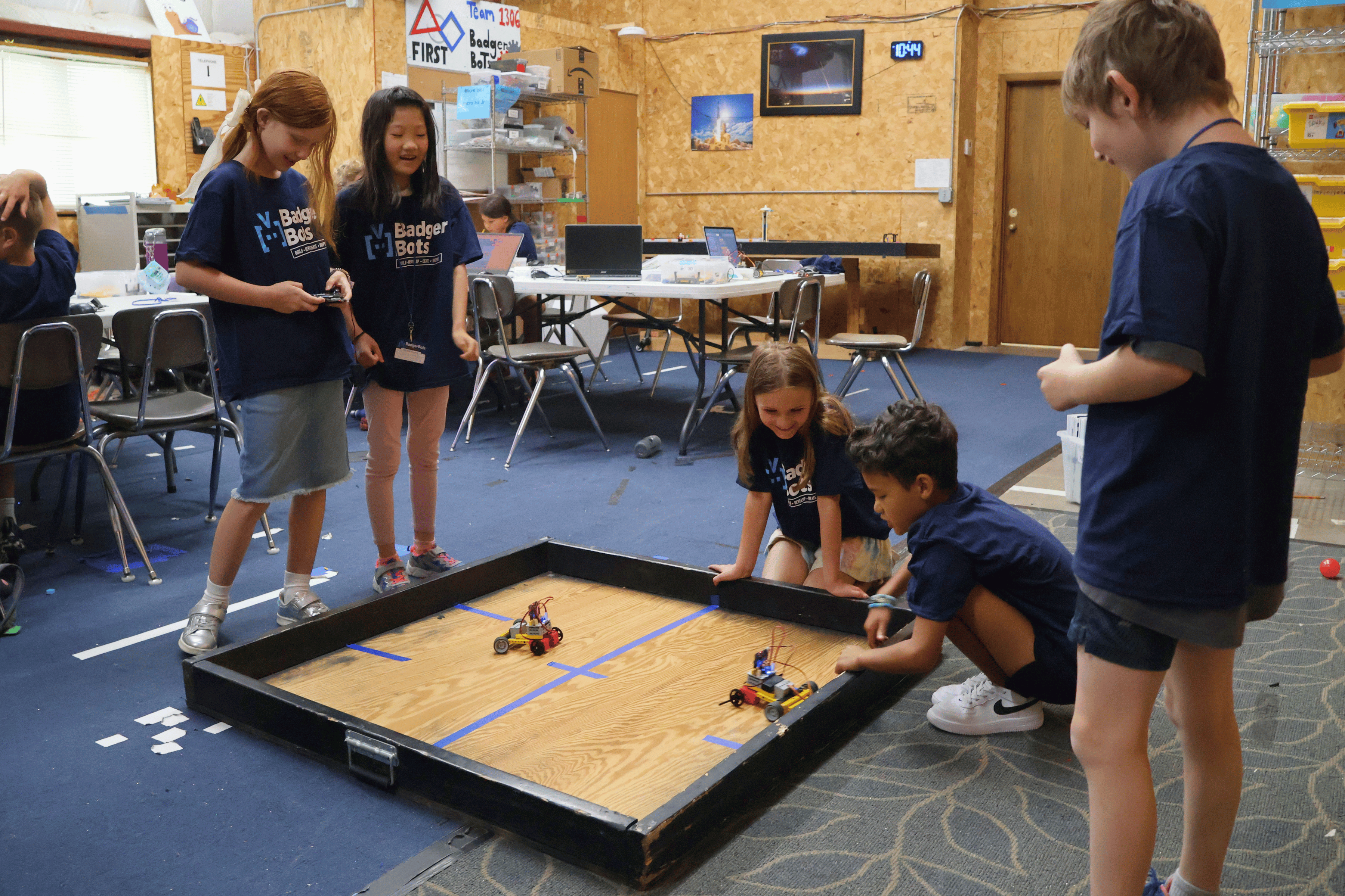 Summer campers play demolition derby with the micro:bit robot cars they built and programmed.